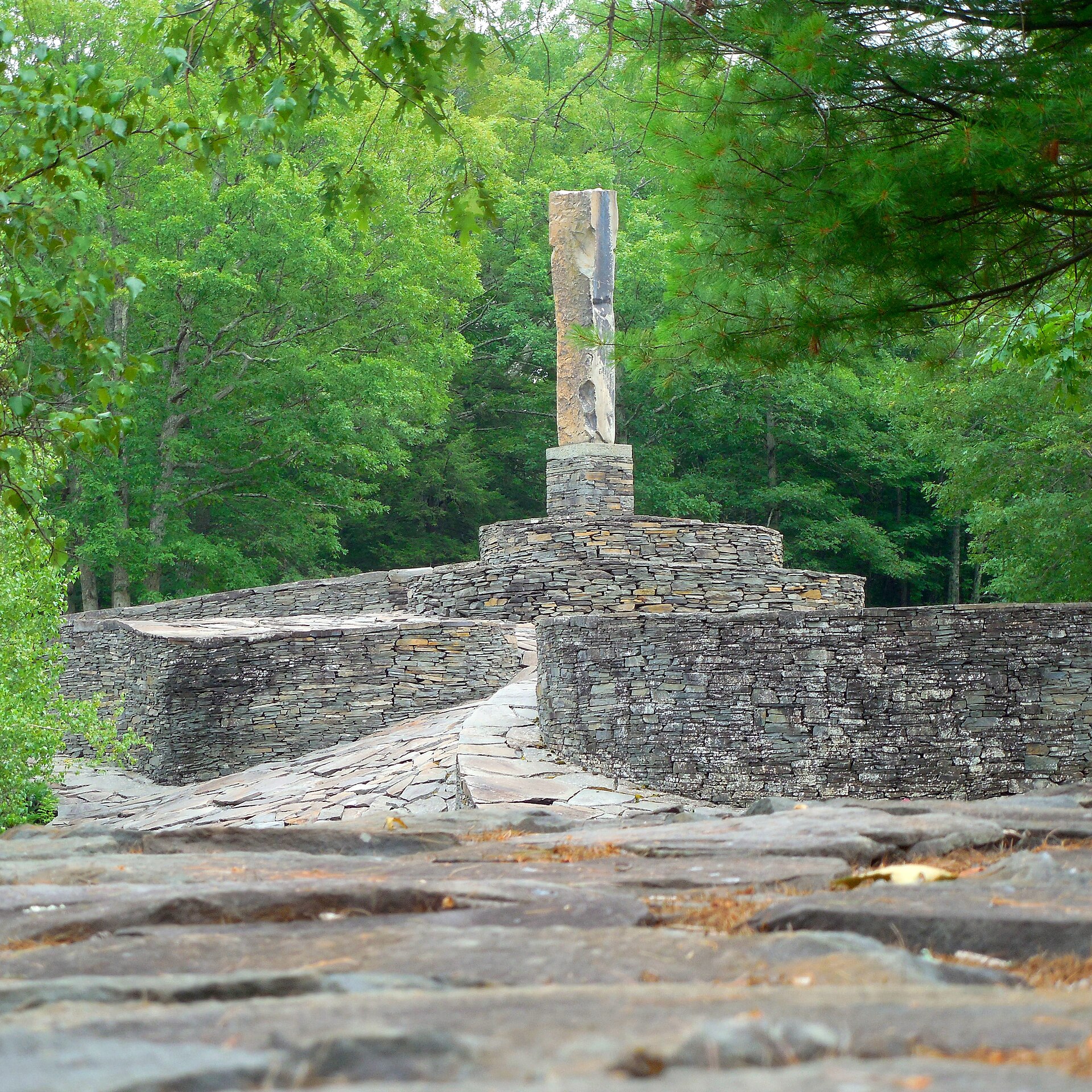 Low view across bluestone walls toward the monolith